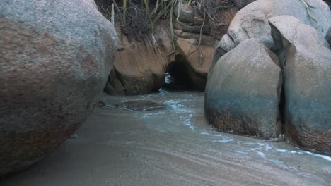 grandes rocas y una cueva en la orilla de la playa con arena blanca en el parque tayrona, colombia