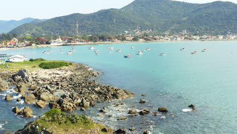 Aerial-view-of-waves-hitting-the-coastline-rocks,-Praia-Armacao,-Florianopolis,-Santa-Catarina,-Brasil