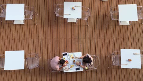 pareja de vacaciones disfrutan de la mañana de verano comiendo y bebiendo desayuno al aire libre en el restaurante del hotel con la camarera sirviendo en la mesa
