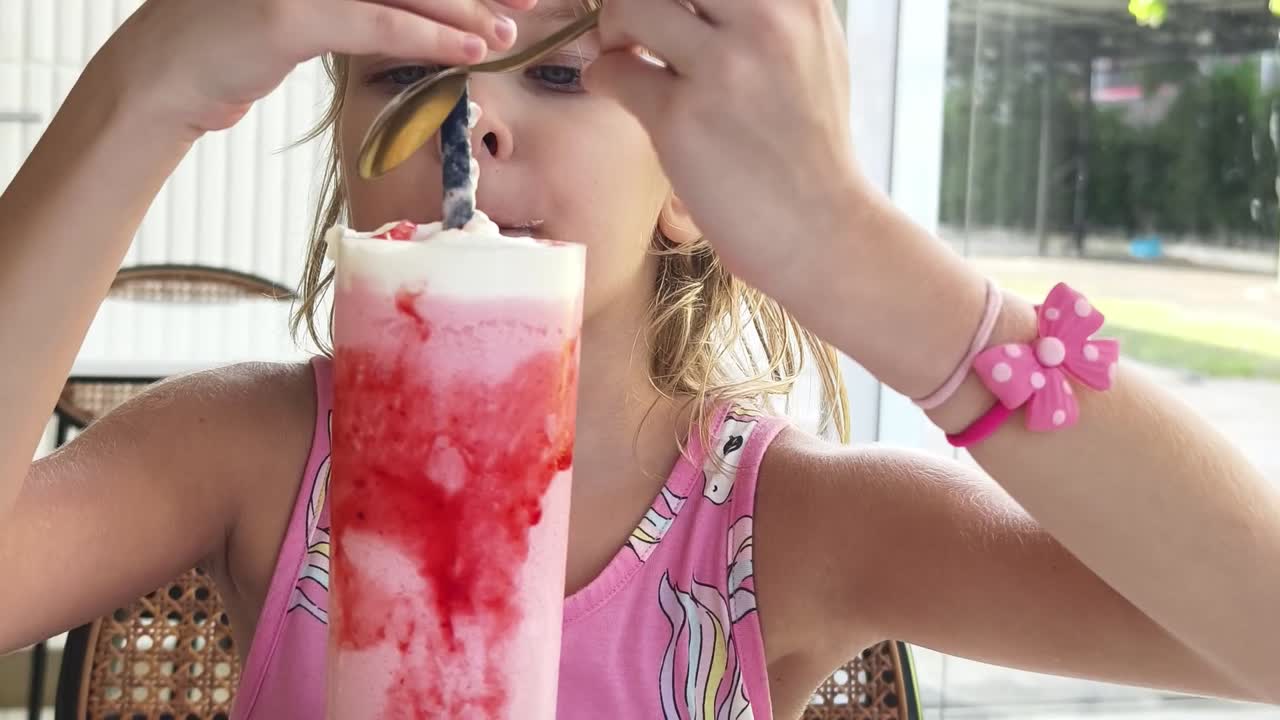 una chica disfrutando de un batido de fresa.