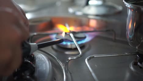 slowmo close up - lighting up gas stove burner fire and a pot of water in kitchen of motorhome