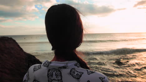 brunette looking at the sunset on the ocean, moody close shot.