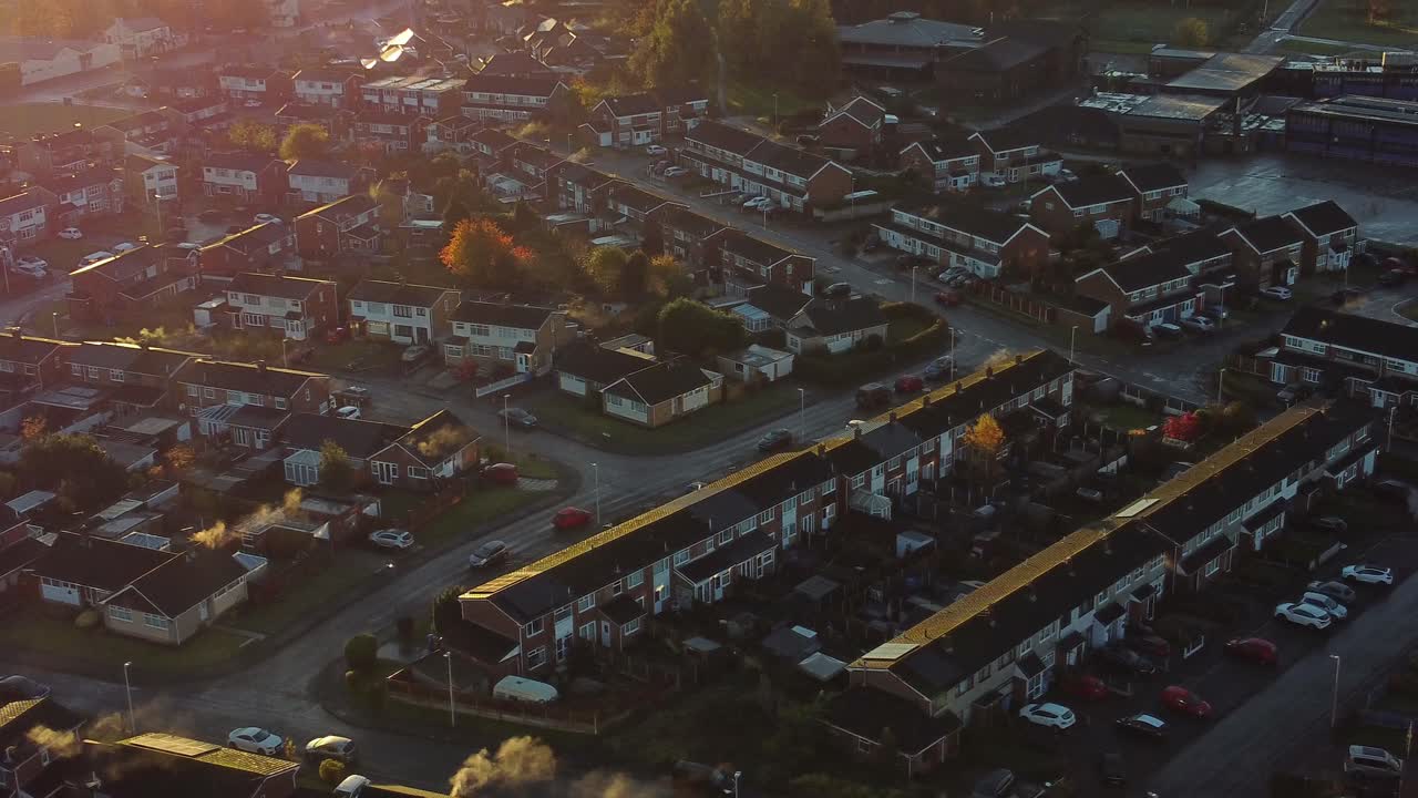 영국 할튼 타운하우스 에스테이트 공중 전망 아침 일출 빛이 가을 색 ⁇ 의 나무와 지붕 위로 누출됩니다.
