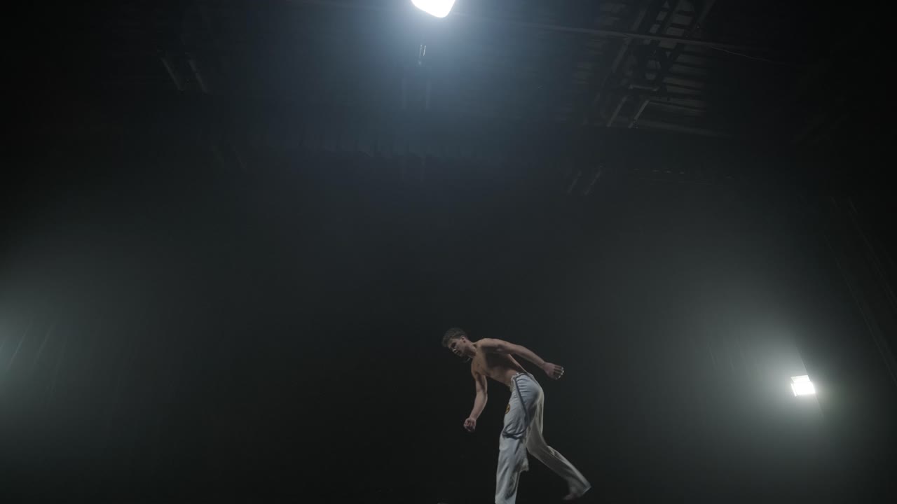 acrobacias de capoeira en un estudio oscuro
