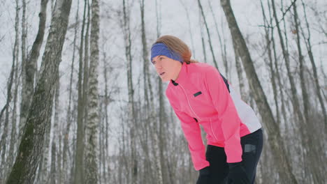 a young woman on a morning jog in the winter forest was tired and stopped to rest and ran on. he recovered his strength and overcame fatigue and continued to run. perseverance and overcoming weakness. striving forward. slow motion. healthy lifestyle