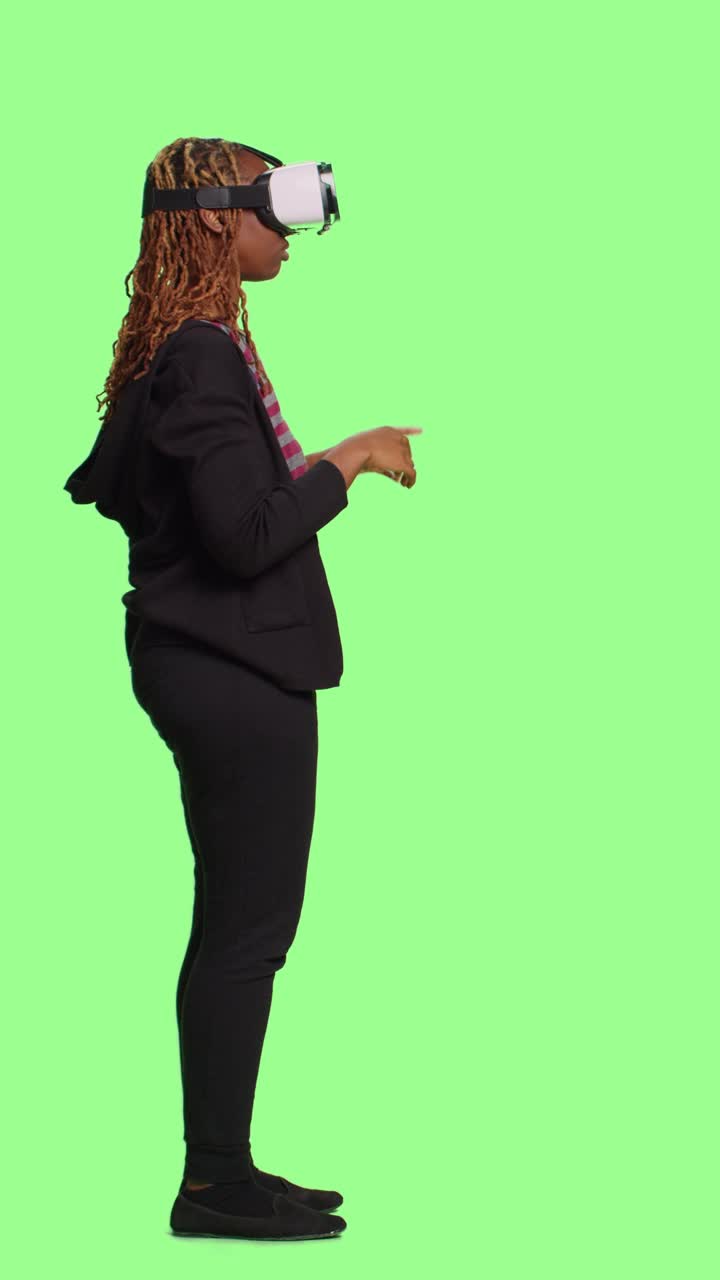 Vertikal video: Glad, leende tjej som använder VR-glasögon med helkropps greenscreen