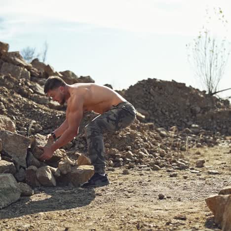 shirtless athlete throwing stones outdoors. young sportsman doing exercise with heavy rocks. motion of stone flying in the air. slow motion.