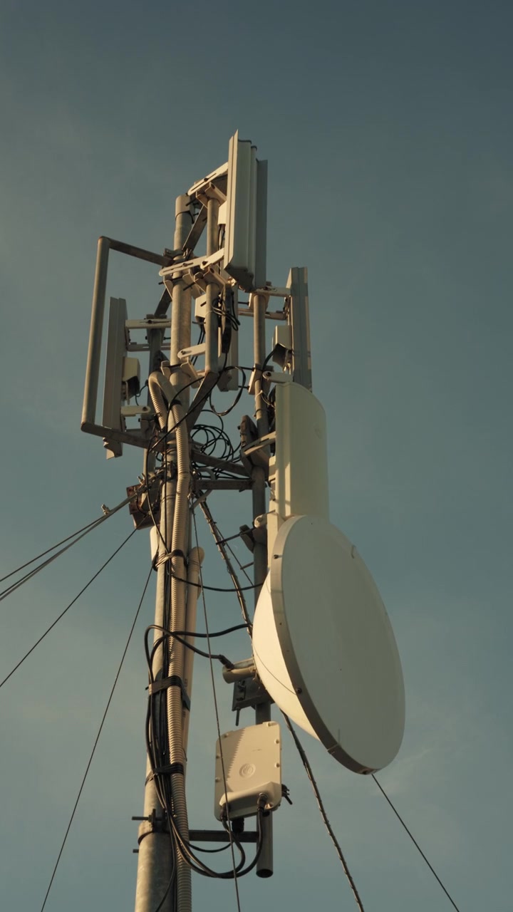Telekommunikationstårn med monterede antenner mod blå himmel