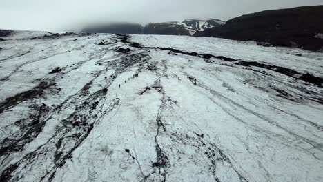 Aerial-landscape-view-of-people-hiking-on-Sólheimajökull-glacier,-Iceland,-during-summer