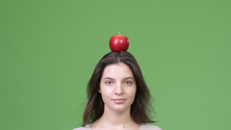 close up shot of young beautiful woman with apple on head