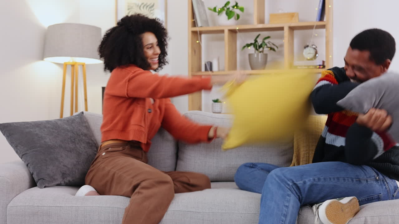 amor, pelea de almohadas y pareja en el sofá
