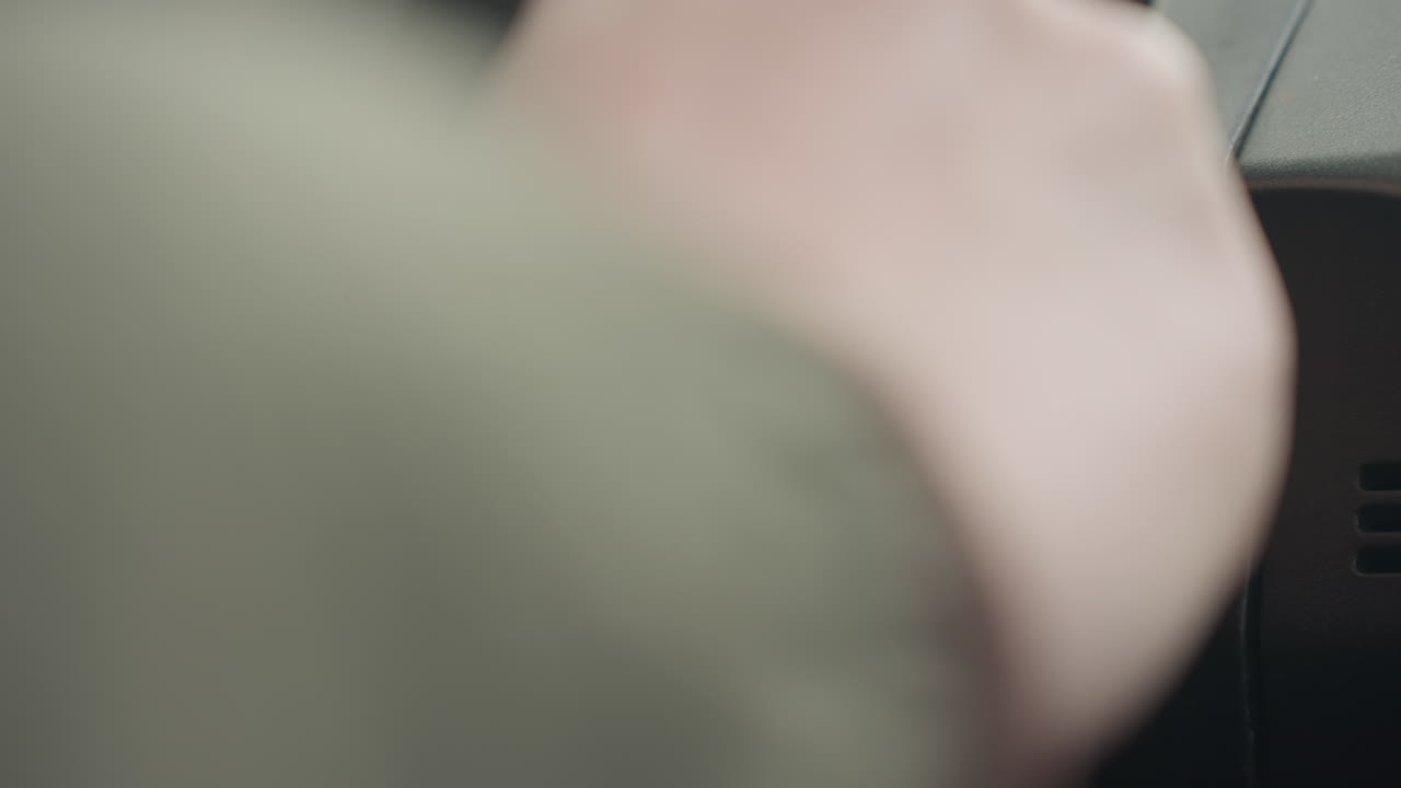 close up of driver hand approaching ignition slot to insert car key, indoor winter scene with car dashboard slightly visible, soft focus emphasizing natural action and ambient vehicle environment
