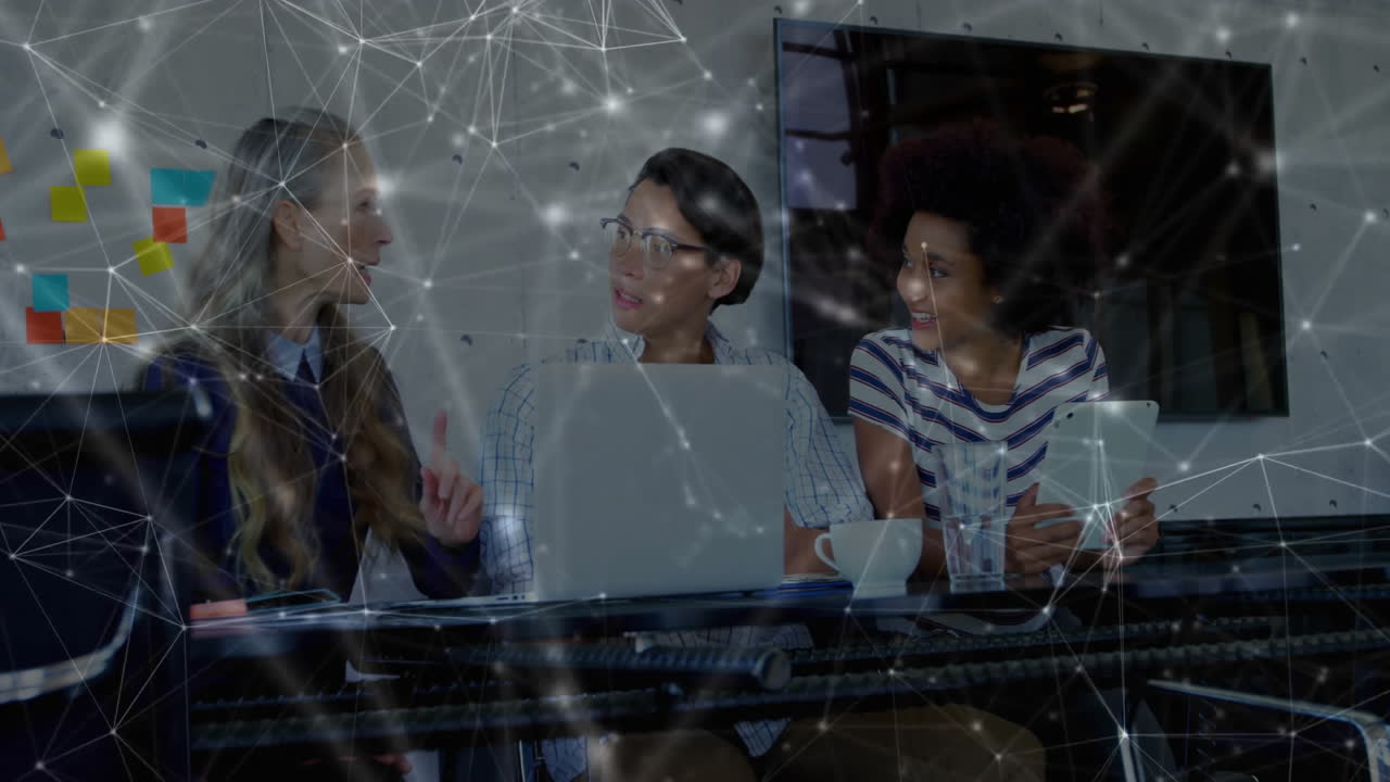Colleagues discussing business strategy with laptop, tablet and animated technology network overlay