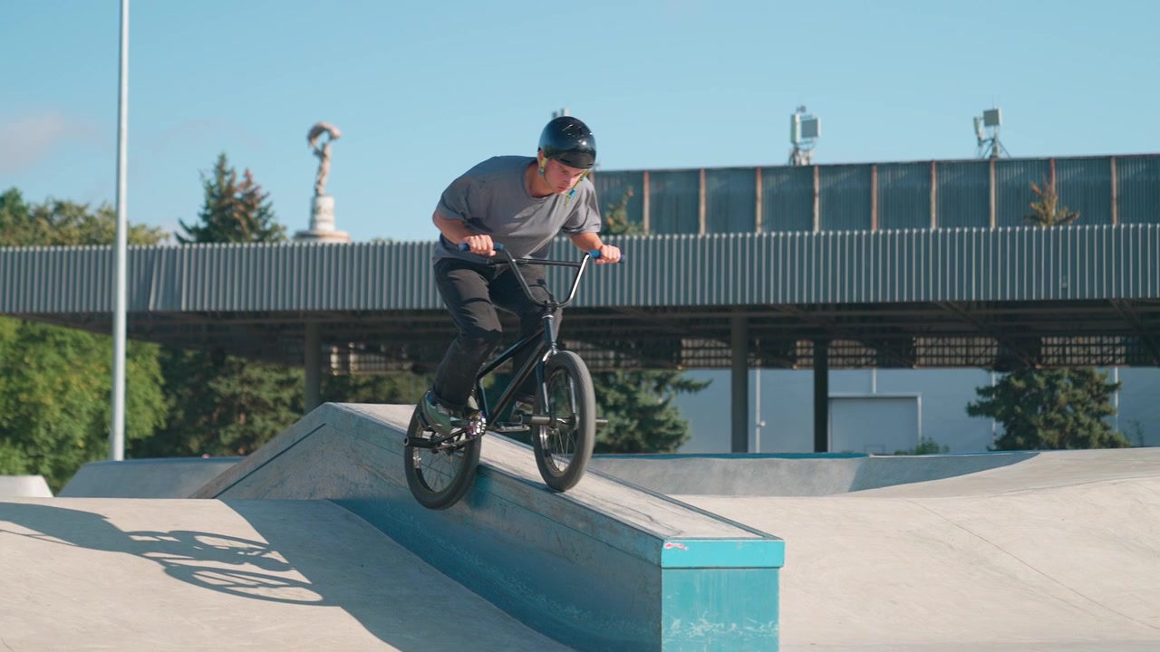 Ragazzo con il casco che esegue un manual in BMX allo skatepark
