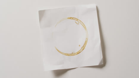 video of close up of piece of paper with coffee mug stain on white background