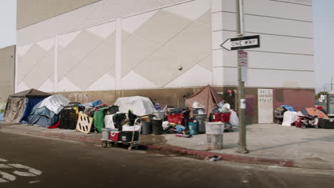 homeless encampment with tents and makeshift shelters on an urban sidewalk