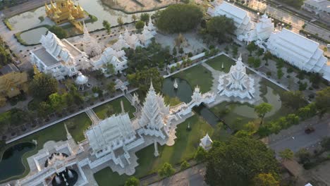 aerial drone of wat rong khun the amazing buddhist white temple and golden temple with mountains and landscape in chiang rai, thailand