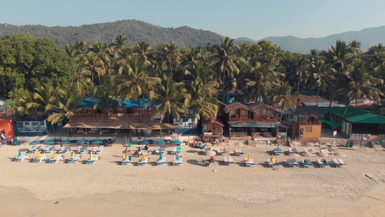 cabañas de palolem beach resort y sillas de descanso cerca de la costa en un entorno exótico - revelación aérea hacia atrás