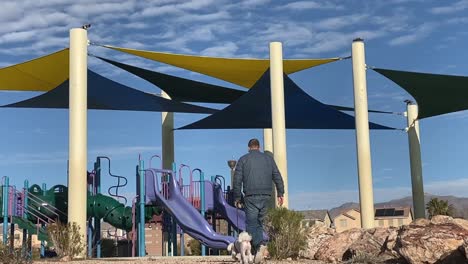 Slow-motion-shot-of-a-man-walking-his-dog-at-playground-park