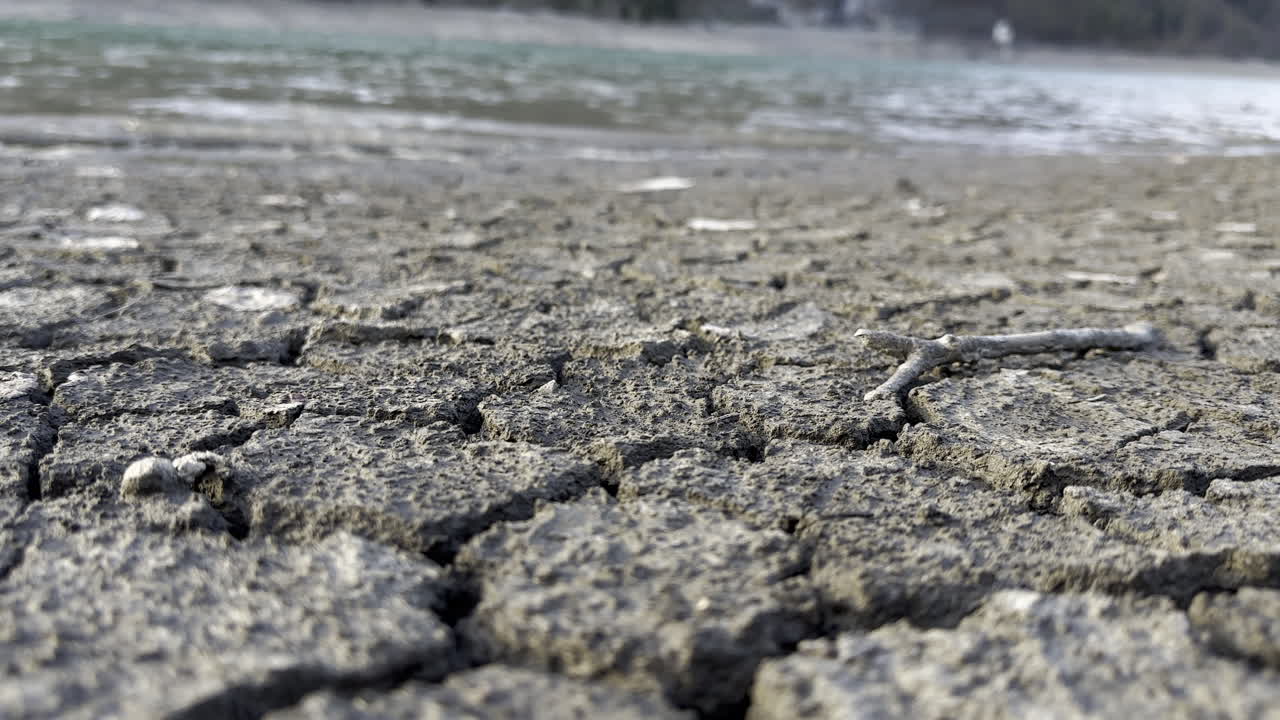 Low shot of The cracked ground contrasts with the abundant water on the shores of the Kl&ouml;ntalersee lake Glarus Kanton, Switzerland