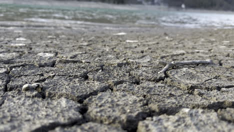 low shot of the cracked ground contrasts with the abundant water on the shores of the klöntalersee lake glarus kanton, switzerland