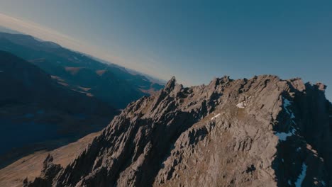 vuelo cinematográfico fpv sobre el pico de las montañas rocosas en noruega durante la puesta de sol dorada