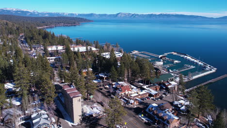 Aerial-View-of-Tahoe-City-Marina,-Lakefront-Homes-and-Blue-Lake-Water-WIth-Mountains-on-Horizon,-California-Nevada-USA