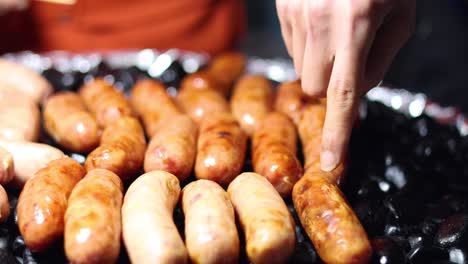 turning sausages over a hot, sizzling grill