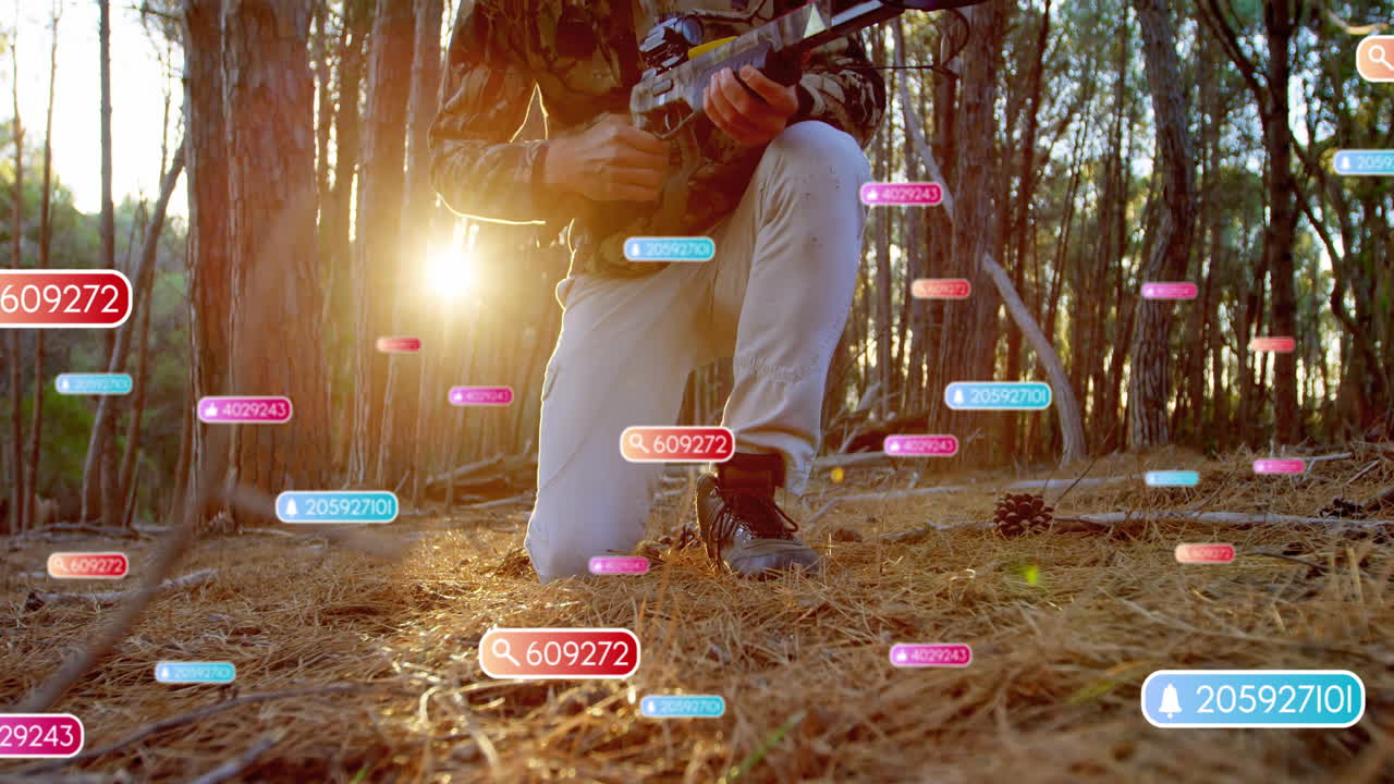 Man kneeling in pine forest, holding rifle-like device showcasing AR icons for technology training