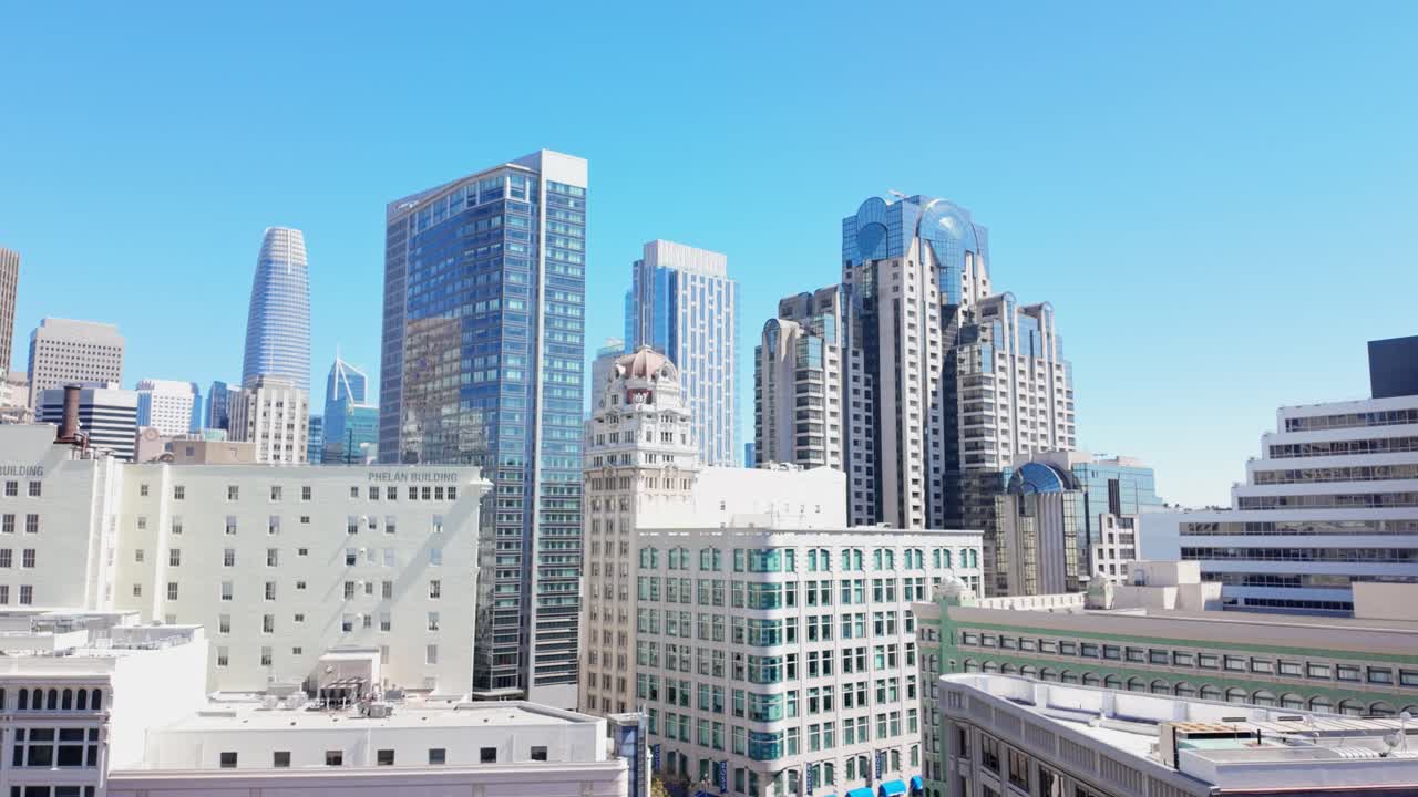 Zoom out view from a rooftop shows San Francisco’s high-rise buildings with a mix of glass, steel, and historic facades