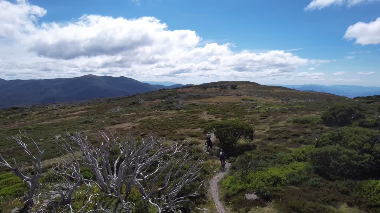 드론은 은 날 산 꼭대기에 있는 경로의 휘어지는 부분을 타고 산악 자전거 라이더를 내려다보면서 천천히 지나갑니다.