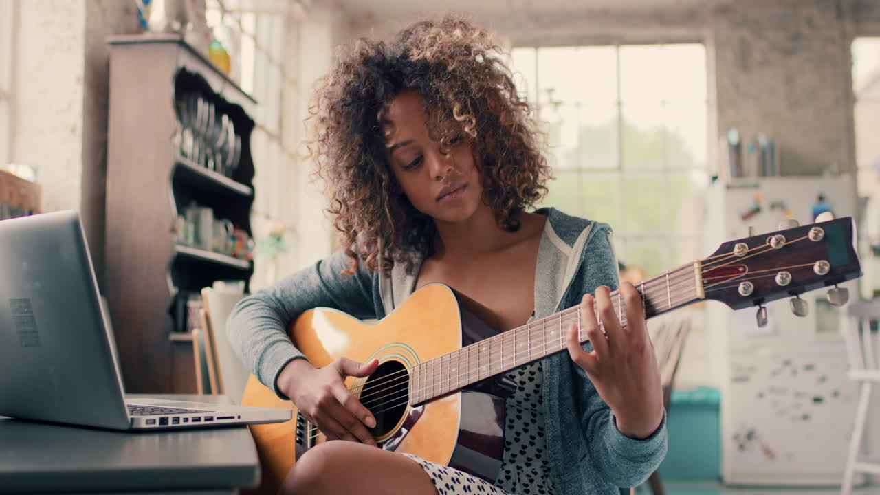 una mujer tocando la guitarra mientras está sentada en casa