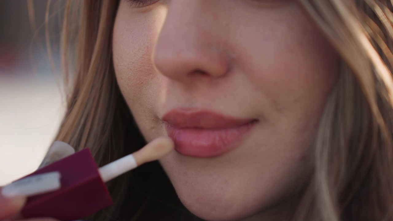 Pretty white woman glossy lip tutorial outdoors in golden light, closeup demo of applicator and shade, playful smile, dewy finish, influencer style stepbystep application and texture reveal