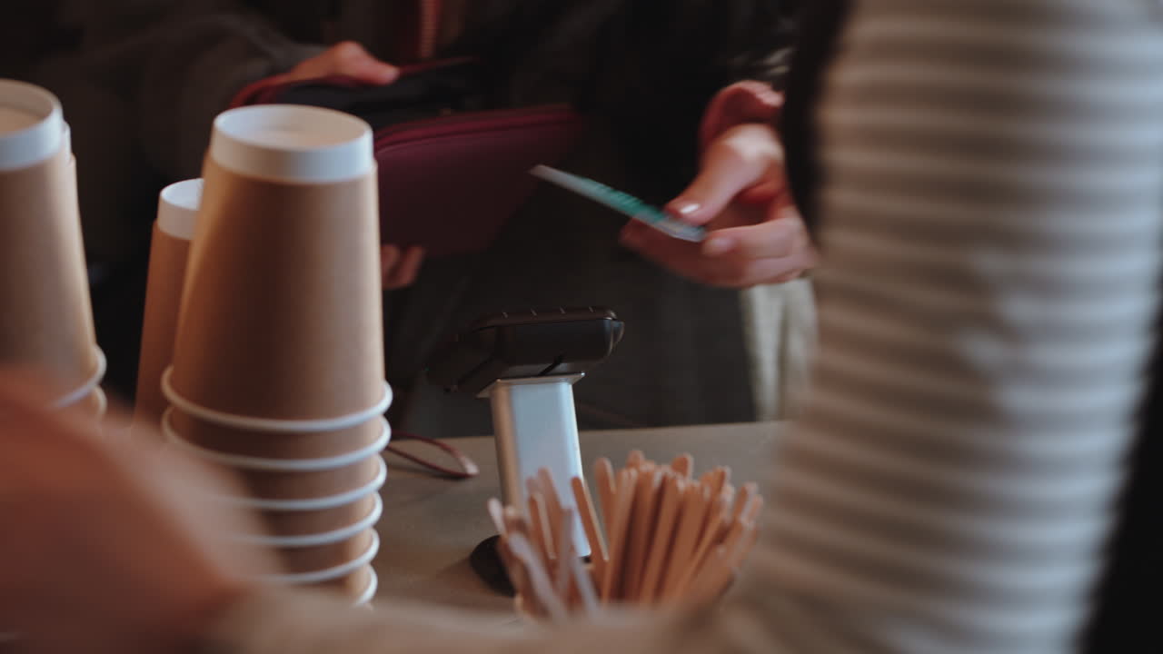 아름다운 여성이 신용카드 거래를 사용하여 지불하고 카페에서 커피를 구입하고 행복한 고객이 서비스를 즐기고 레스토랑에서 돈을 쓰고 있습니다.