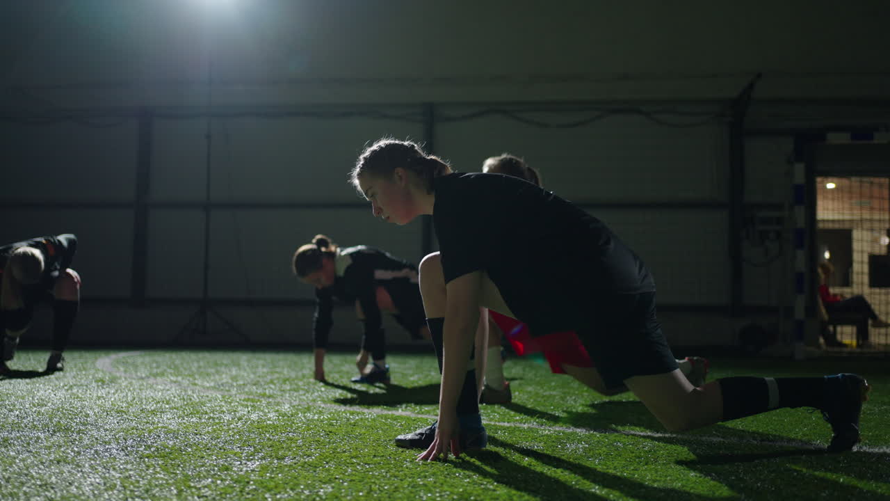 un grupo de jóvenes jugadoras de fútbol femenino calentándose en el interior