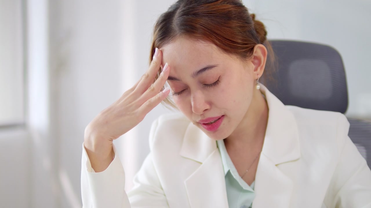 オフィス環境で仕事中にストレスの兆候を見せる女性。