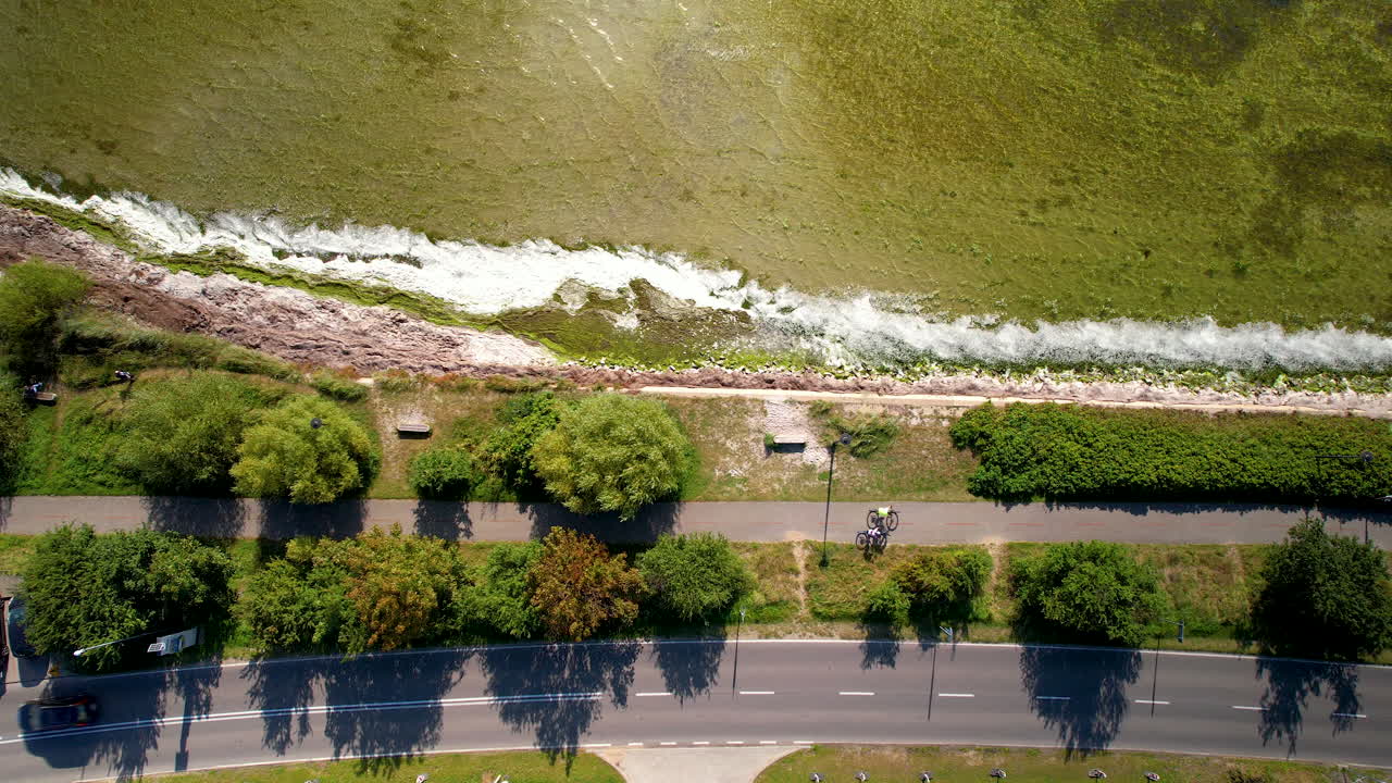 바다의 파도가 바위에 부히면서 해안가의 도로와 평행한 길에 자전거를 타는 자전거