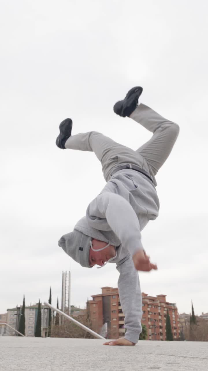 Breakdancer performing handstand freeze in urban setting