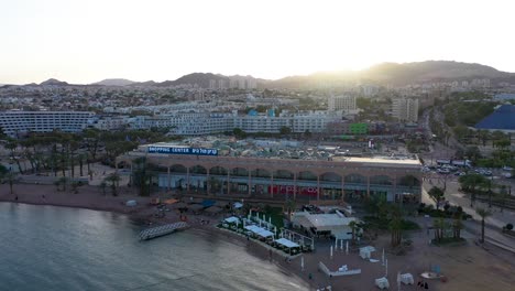 big shopping center in the city center of eilat where tourists and locals buying there needs with the sun just over the mountains peaks