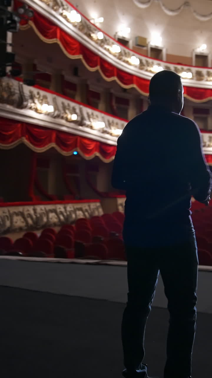 Actor during the rehearsal in large theater. Man performing on stage in front of empty auditorium. Consequences of pandemic. Vertical video