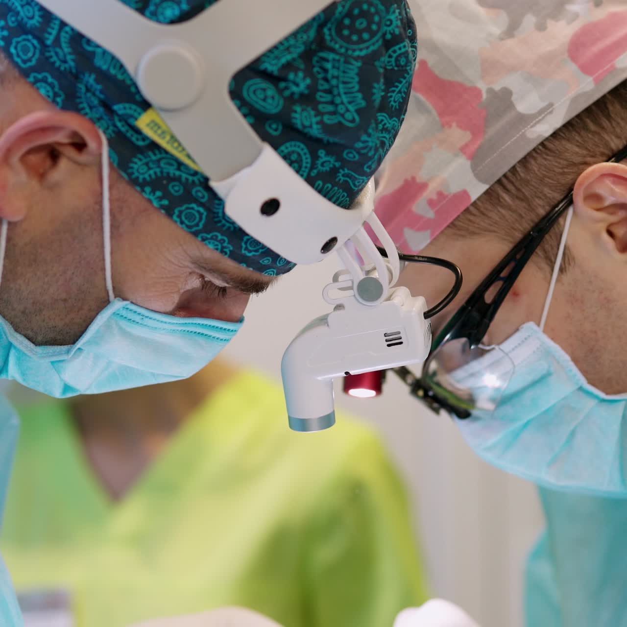 Doctors work in operating theater. Faces of medical specialists in masks and magnifying glasses on head during the operation. Close-up.