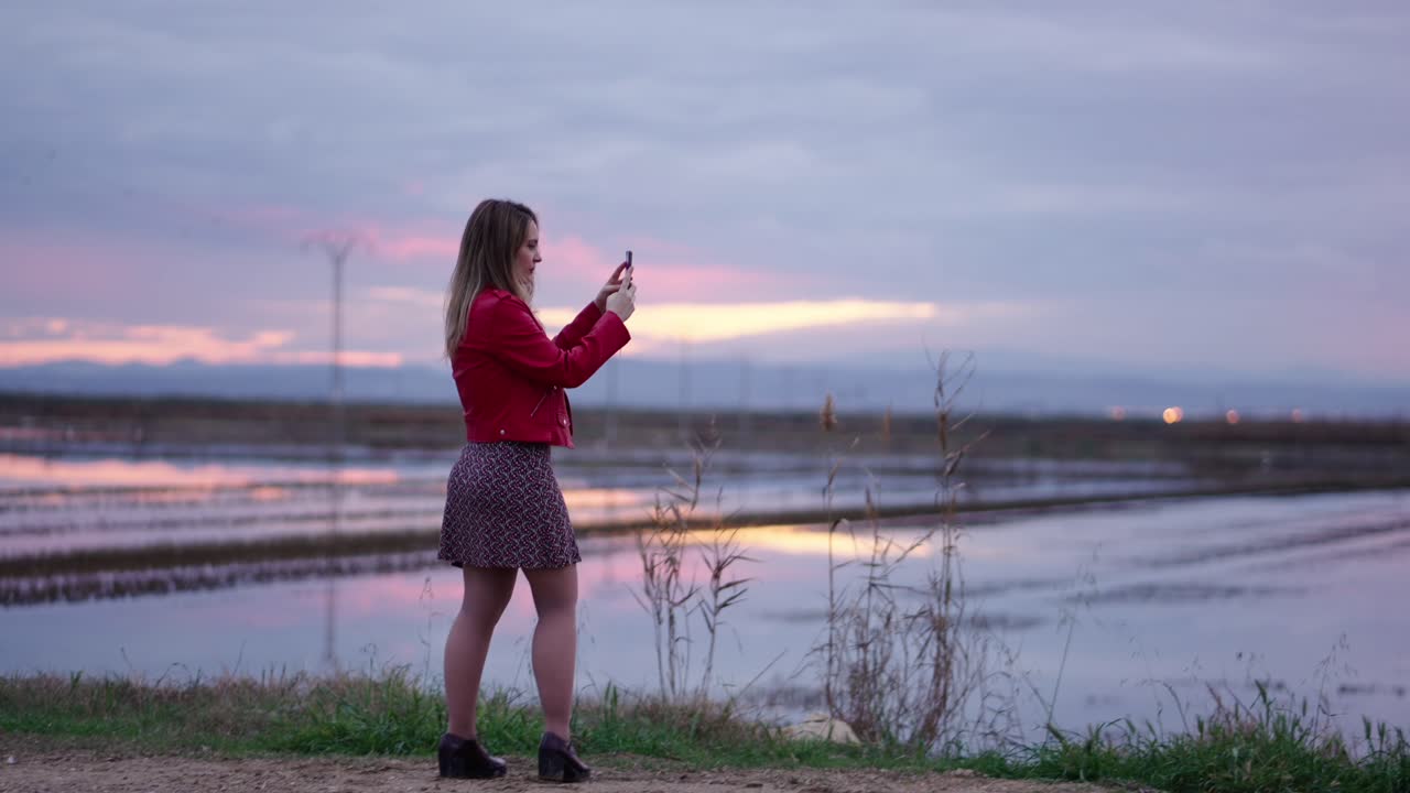 Woman Taking Photo of Sunset over Fields