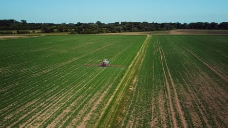 aerial footage of a tractor watering green fields in western europe filmed on a sunny day