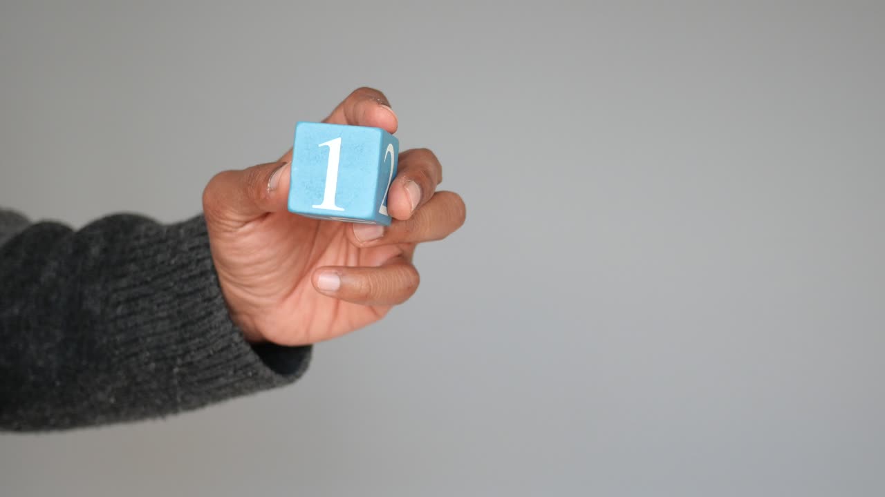 mano sosteniendo un bloque de madera azul con el número uno