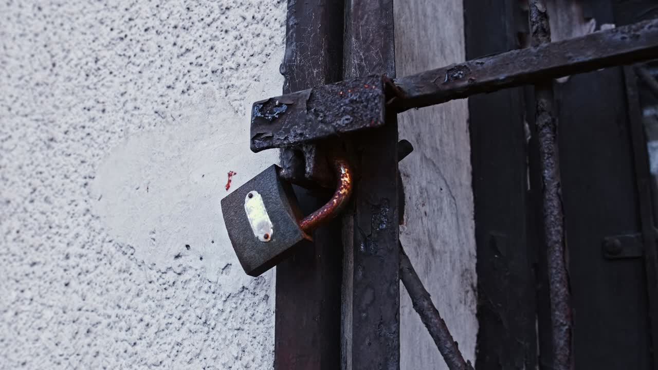 puerta vieja y dañada del edificio abandonada durante la crisis económica asegurada con un candado y un llave oxidados