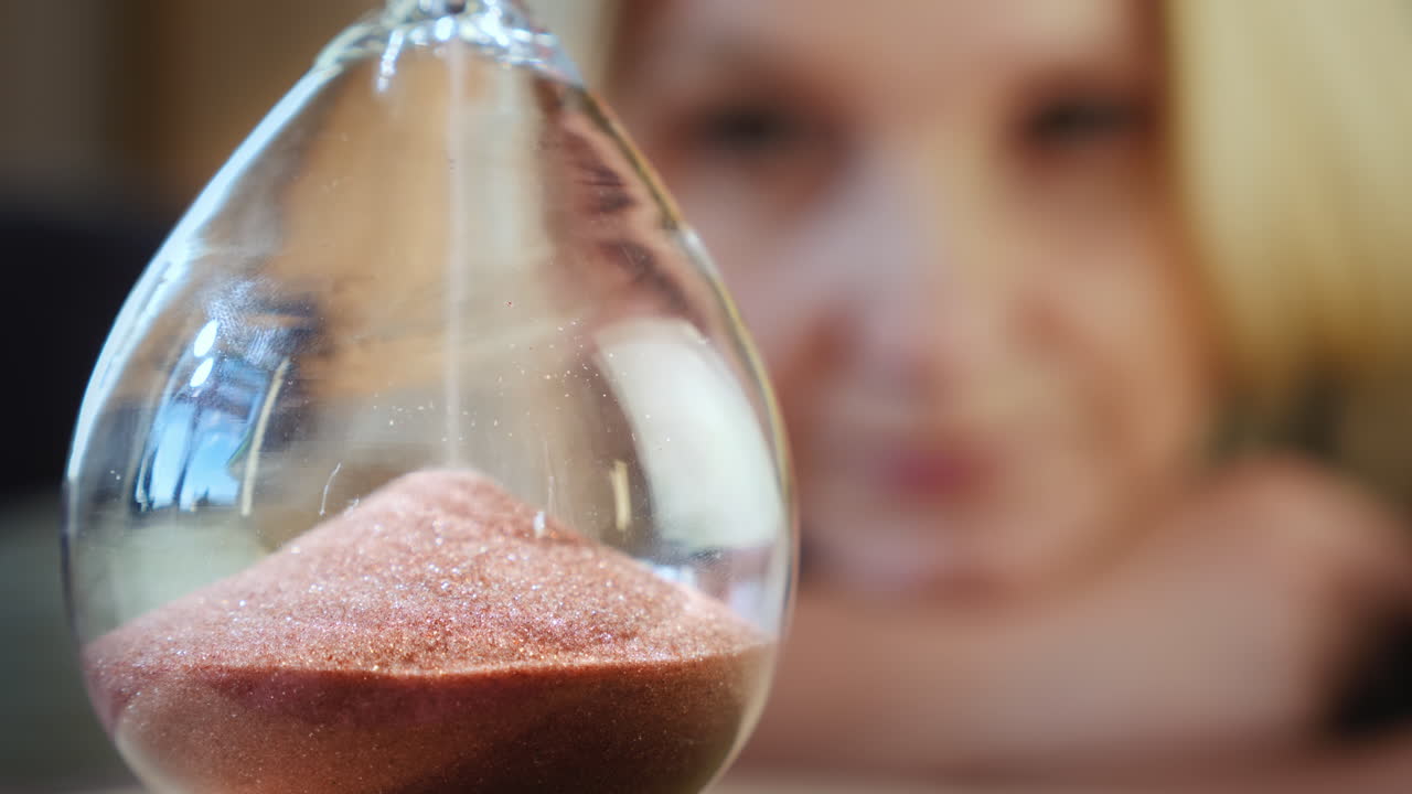 여자는 자기 격리하면서 모래 시계를 본다