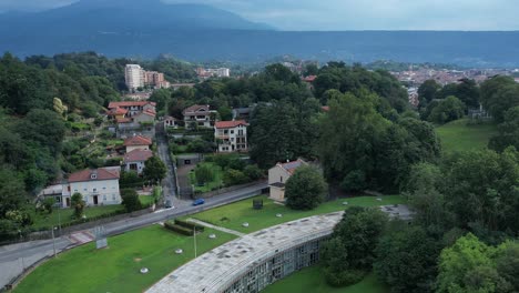 talponia, the semi-subterranean residential unit in ivrea, piedmont, designed by gabetti isola in 1968, set in a curved green park at the city forest edge, drone pull away shot slow motion, italy