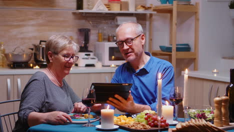 old man showing photos on tablet