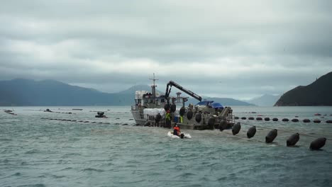 SLOWMO---Man-on-small-inflatable-boat-approaching-mussel-boat-at-plantation-on-cloudy-day