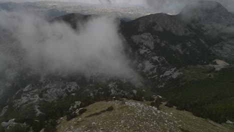 aerial view towards the huge cliff with some fog in the middle of the lovcen mountain in montenegro